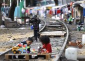 Hecho. Menores migrantes juegan sobre la vía de un campamento, en Ciudad de México (México), entre muros de madera, lonas y otros materiales reciclados.