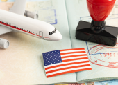 Referencial. Pasaporte con sellos de entrada y salida, junto a una bandera de EE.UU. y un avión en miniatura, simboliza las tensiones migratorias entre Tailandia y Estados Unidos.