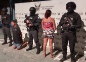 Policías armados custodian a los dos detenidos durante el operativo “Libertad 24” en Muisne, sur de la provincia de Esmeraldas.