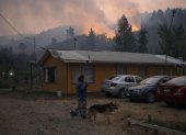 Una mujer camina cerca a un incendio forestal en la comuna de Chaimávida, en Concepción a unos 491 km aproximadamente de Santiago (Chile).
