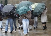 Varias personas se protegen de la lluvia en el noroeste de España.