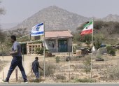 La gente camina junto a las banderas de Israel y Somalilandia que ondean juntas en la entrada de una granja de frutas.