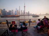 Fotografía de archivo de un grupo de personas frente al paisaje urbano de Shanghai.