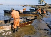 Fotografía de referencia de trabajadores petroleros contratados por la paraestatal Petróleos Mexicanos que limpian en una zona de un derrame de crudo.