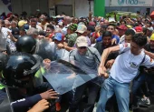 Personas exigen aumentos salariales mientras se enfrentan con integrantes de la policía en una manifestación este jueves, en Caracas (Venezuela).