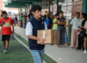 Integrante de la Oficina Nacional de Procesos Electorales (ONPE) carga una caja para empezar la instalación de una de las mesas de votación en un colegio de Lima.