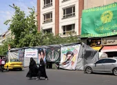 Mujeres caminan junto a pancartas instaladas a lo largo de la carretera con imágenes del asesinado líder supremo de Irán, el ayatolá Ali Khamenei (izquierda), y del líder supremo, el ayatolá Mojtaba Khamenei, en Teherán.