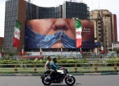 Personas circulan en motocicleta cerca de una valla publicitaria antiestadounidense con una foto de Donald Trump en la plaza Valiasr de Teherán, Irán, el 6 de mayo de 2026.