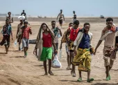 Miembros de la OIM asisten a un migrante etíope exhausto en una remota zona desértica.