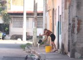 Una mujer limpió la vereda en el sector donde fue abandonado el cadáver de un hombre, frente a una escuela, en el Guasmo Sur de Guayaquil.