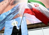 Una mujer con velo sostiene la bandera nacional de Irán frente a una enorme valla publicitaria antiestadounidense en Teherán, Irán, el 11 de mayo de 2026.