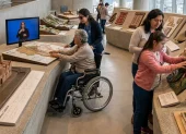 Una persona que utiliza silla de ruedas interactúa con una maqueta táctil de una catedral en un museo moderno y luminoso