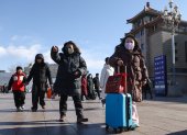Personas caminan en las calles de Beijing, en China, al fondo un edificio.