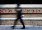 Un policía camina frente a un grafiti en La Paz, en medio de las protestas que marcan la primera crisis política del Gobierno de Rodrigo Paz.