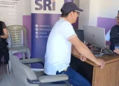 Una persona pregunta a técnicos del SRI sobre beneficios tributarios.