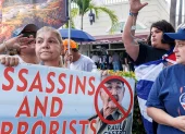 Cubanos en el exilio sostienen un cartel que dice "Asesinos y terroristas" mientras celebran el Día de la República de Cuba en Miami, Florida, EE. UU., el 20 de mayo de 2026.