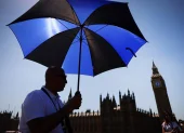 Un hombre se protege del sol con un paraguas en Londres.