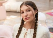 Fotografía promocional de Yami Safdie en un ambiente interior con tonos pastel. La artista aparece sentada en el piso, con trenzas, blusa blanca tejida y una estética visual vinculada al universo de Querida Yo.