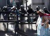 Una mujer aimara camina frente a un grupo de policías durante una protesta por quinta semana consecutiva este 1 de junio de 2026, en La Paz (Bolivia).