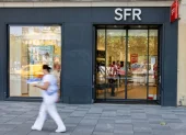 Una persona pasa al pide de una tienda de SFR.