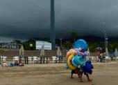 Fotografía referencial, vendedores caminan en una playa.