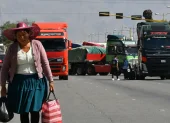 Una mujer quechua camina frente a vehículos de una caravana de transportistas para exigir el levante de los bloqueos de carreteras este lunes, en Cochabamba (Bolivia).