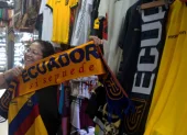 Una clienta sostiene una bufanda tricolor con el lema "Ecuador, sí se puede" en un local repleto de prendas alusivas a la selección, en plena fiebre por la moda mundialista.