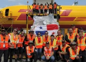 Personal de carga junto a un envío con la bandera de Panamá en un avión de DHL