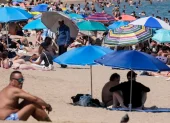 Turistas buscan sombra bajo sombrillas en playas europeas durante la ola de calor.