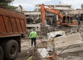 Una persona camina entre máquinas y escombros de edificios colapsados este lunes, en La Guaira (Venezuela).