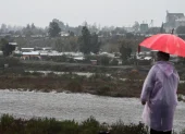Una persona observa el caudal del Río Mapocho al costado de un campamento en riesgo de inundación en la comuna de Talagante (Chile)