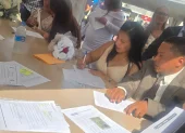 Una de las parejas firma el acta que oficializa su unión durante el matrimonio colectivo celebrado en Parque Samanes.