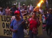 Campesinos sostienen banderas y velas en una vigilia en rechazo al decreto ejecutivo que ordena la clausura de los cementerios comunitarios.