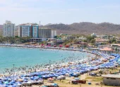 Referencial.Turistas disfrutan de la playa bajo sombrillas en la Costa ecuatoriana, mientras el Inamhi anticipa condiciones variables para el feriado.