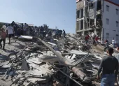 Personas caminan sobre los escombros de un edificio colapsado este lunes, en Cali (Colombia).