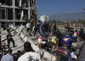 Personas caminan sobre los escombros de un edificio colapsado este lunes, en Cali (Colombia)