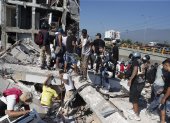 Personas caminan sobre los escombros de un edificio colapsado este lunes, en Cali (Colombia). Al menos 20 edificios sufrieron graves daños por consecuencia del terremoto de magnitud 7,4 que sacudió la mayor parte del país, con epicentro en la zona del Pacífico.