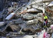 Un integrante de organismos de socorro camina sobre los escombros de una edificación destruida tras el terremoto de magnitud 7,4 que sacudió la víspera la mayor parte de Colombia, este martes en Pereira (Colombia).