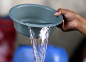El hondureño Darwin Ordoñez llena un recipiente con agua este 14 de agosto de 2026, en Tegucigalpa (Honduras).