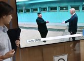 Una mujer pasa junto a una pantalla de televisión que muestra reunión entre el presidente Donald Trump y el líder norcoreano Kim Jong Un, en estación de tren de Seúl.