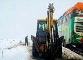 Operarios trabajando con maquinaria amarilla para limpiar una carretera durante una nevada en La Paz (Bolivia).