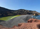El Charco de los Clicos sorprende por sus aguas verdes rodeadas de arena negra, rocas rojizas y el azul del océano.