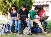 Group of teenagers social networking using several tech devices in high school