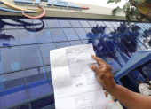 Una persona presenta su planilla de luz en CNEL.