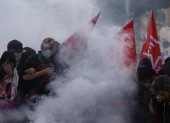 Estudiantes de secundaria permanecen en medio de gases lacrimógenos mientras estallan enfrentamientos entre estudiantes y la policía antidisturbios.