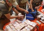Integrantes de la Fuerza Especial de Lucha Contra el Crimen (FELCC) de Bolivia cuentan billetes que fueron encontrados en una ambulancia.