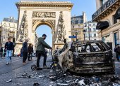 La gente pasa junto a un coche calcinado tras los enfrentamientos entre la policía antidisturbios y los manifestantes en París.