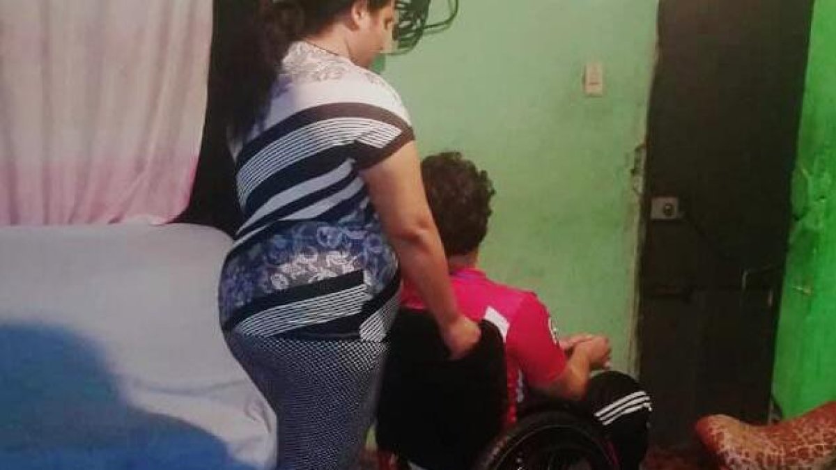 Una madre moviliza a su hijo que tiene discapacidad.