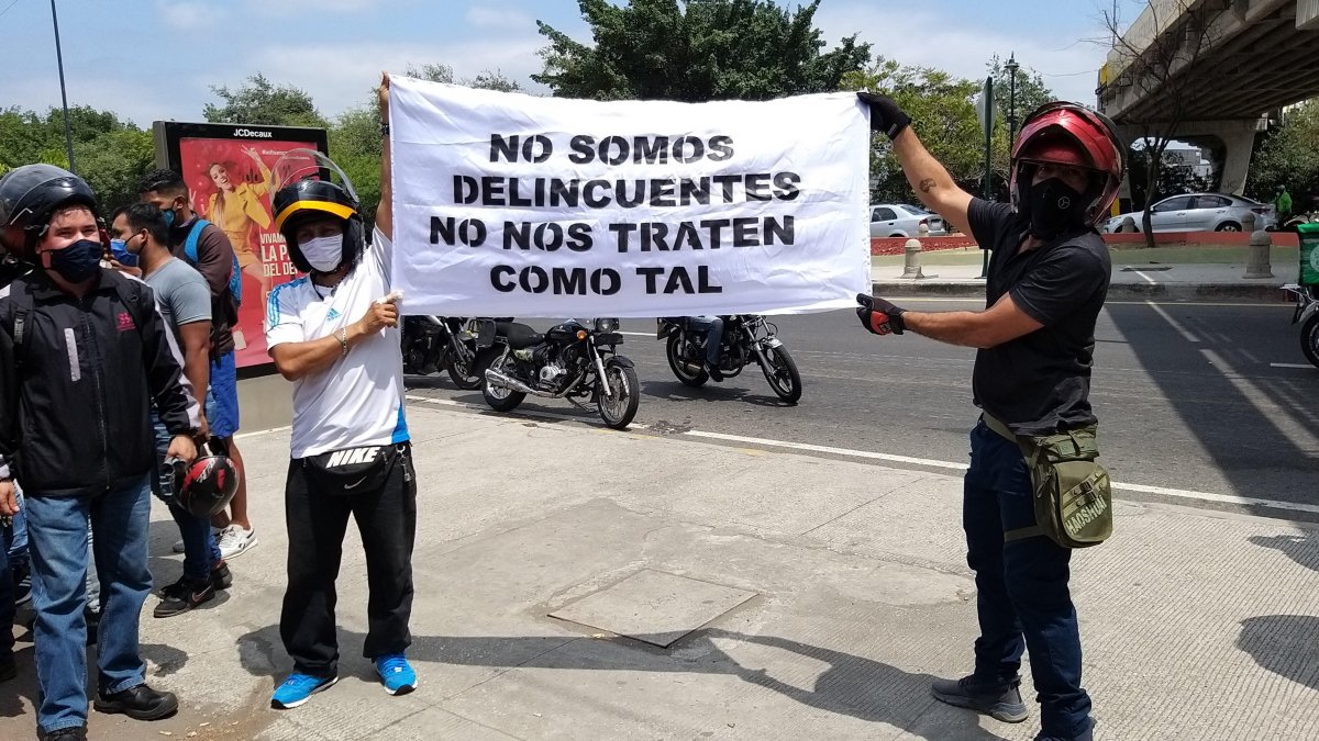 Dos motociclistas sostienen un cartel en el que piden no ser tratados como delincuentes.