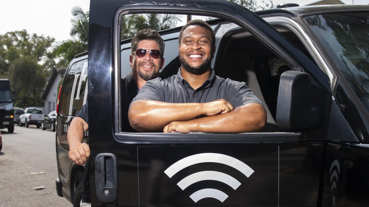 Roman Reyna y Kevin Watson (d), posan con una de las furgonetas equipada como punto de wifi.